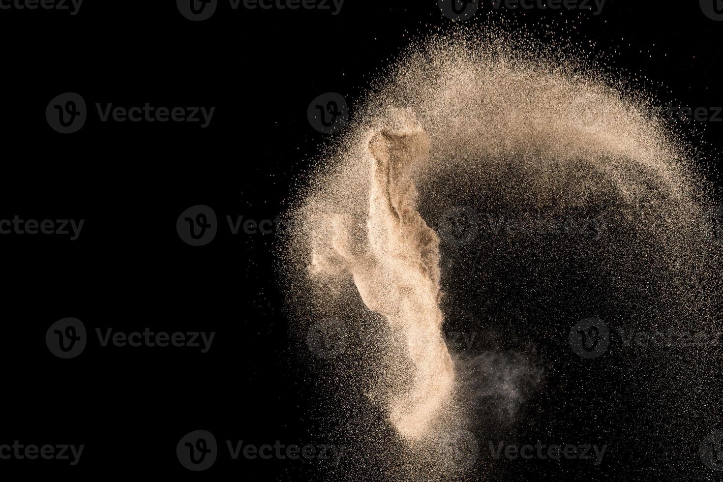 Dry river sand with stone explosion. Yellow colored sand splash agianst dark background. photo