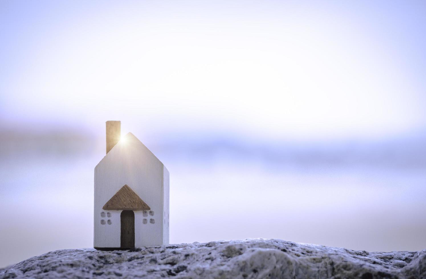 The miniature white house on stone with background of sea beach. Family lifestyle and building or rent concept. photo