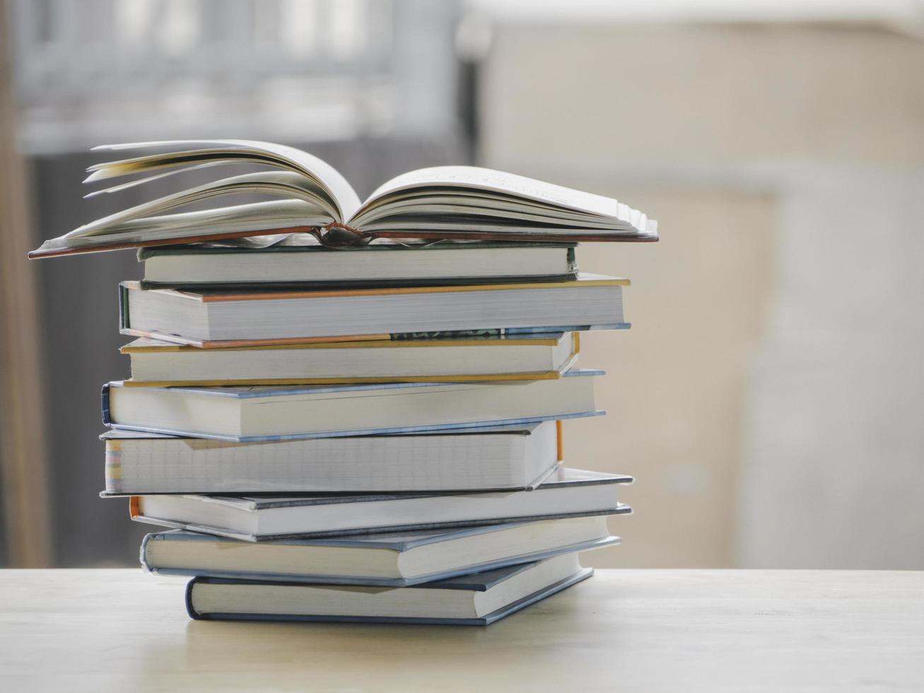 A simple composition of many books, stack or pile of books on wooden table, one of them open with copy space. photo