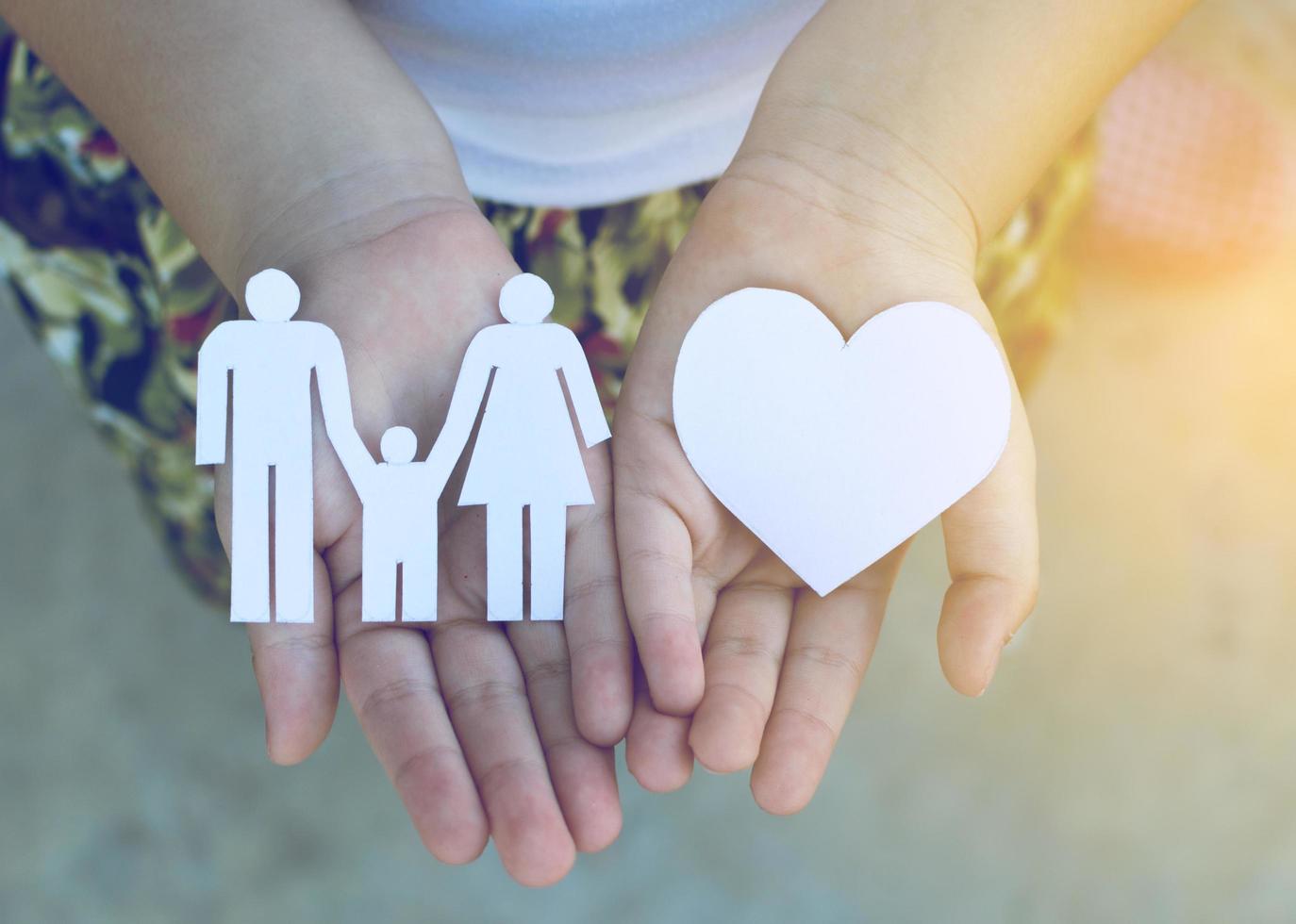 manos de niños sosteniendo un pequeño modelo de corazón y familia, concepto de familia foto