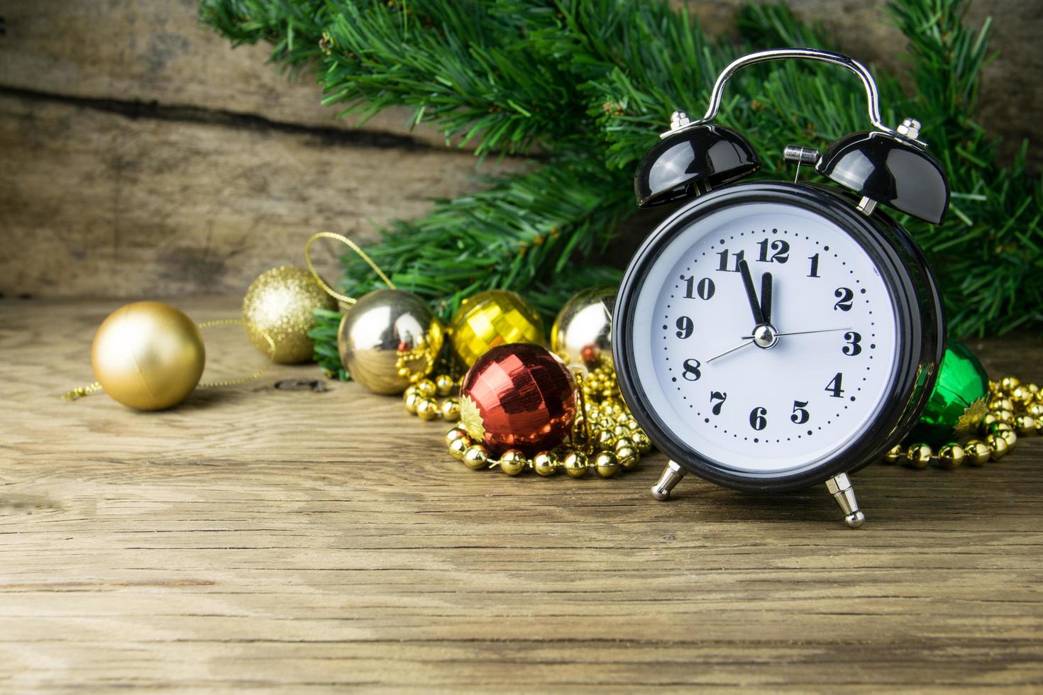 Alalrm-clock and Christmas baubles on wooden background photo