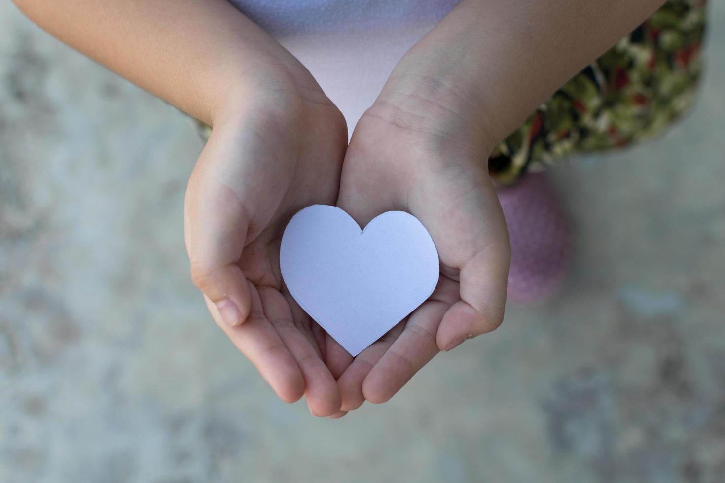 manos de niños sosteniendo un pequeño modelo de corazón y familia, concepto de familia foto