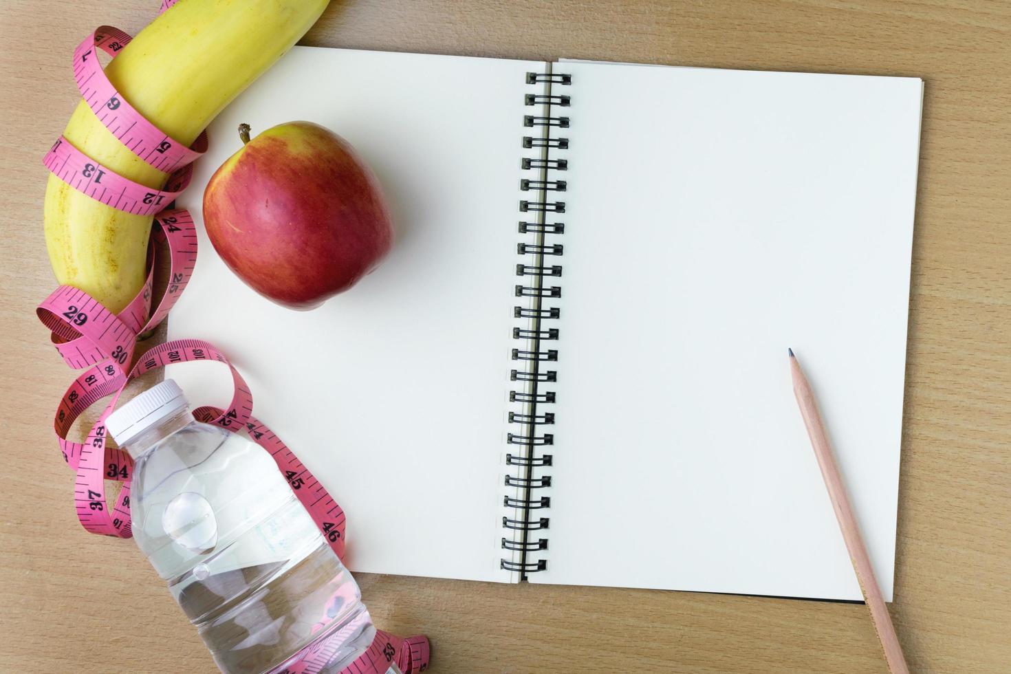 Healthy eating concept, tape measure, fruit and water bottle on a wooden background, blank copy space notebook photo