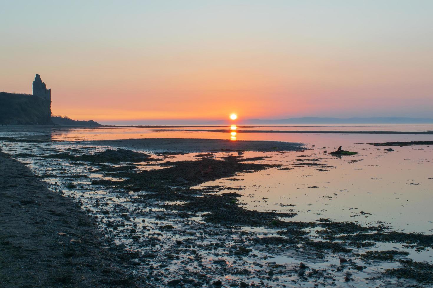 puesta de sol sobre la playa junto al castillo foto