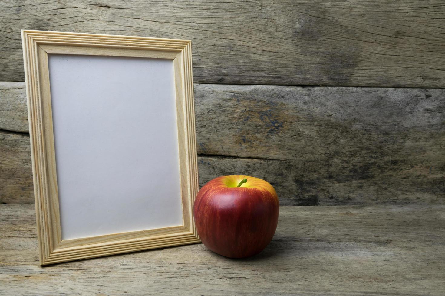 Wood photo frame and red apple on wooden table