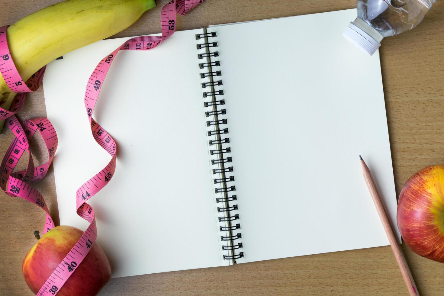 Healthy eating concept, tape measure, fruit and water bottle on a wooden background, blank copy space notebook photo