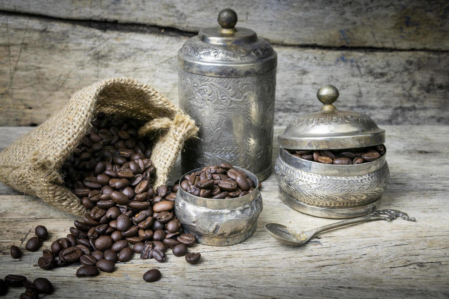 Silver cup and Coffee beans in sackcloth bag on wooden background photo