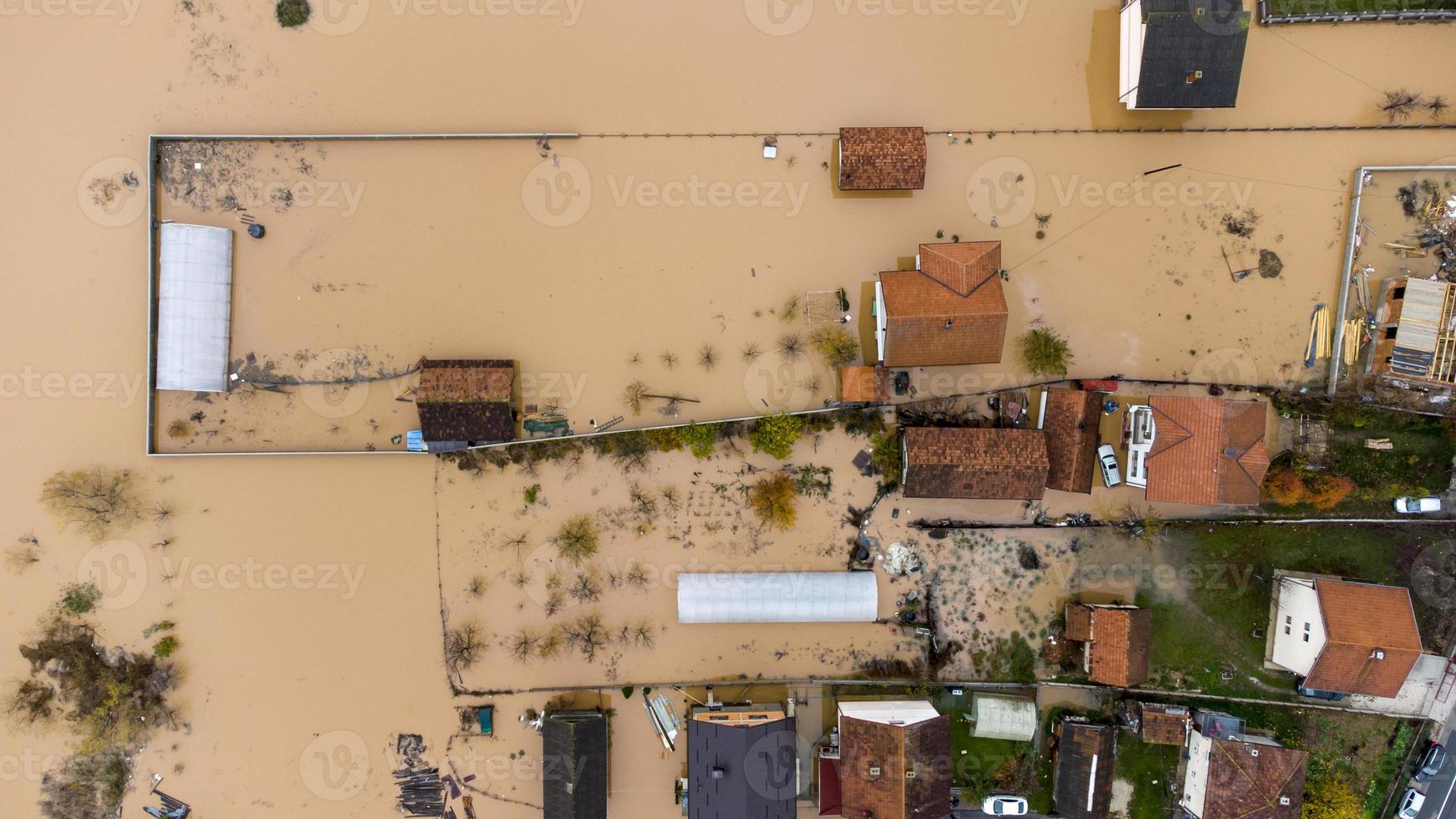 Aerial drone view of torrential rain causes flash floods in residential areas. Houses and roads surrounded by water. Climate change. Heavy rainfall consequences. photo