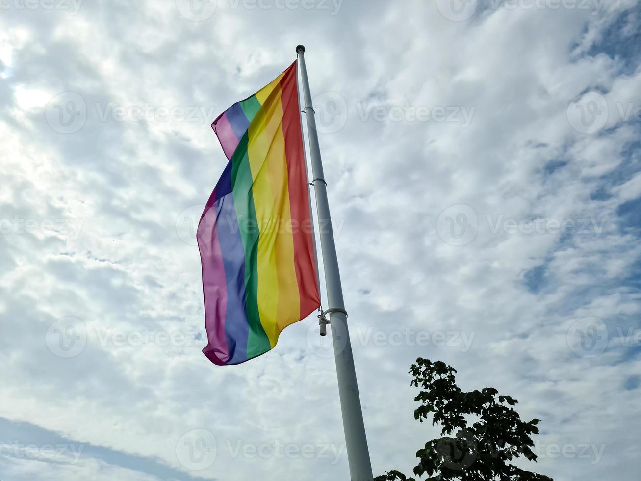 Rainbow pride flag on a flag pole. Lgbt community symbol in rainbow colors. photo