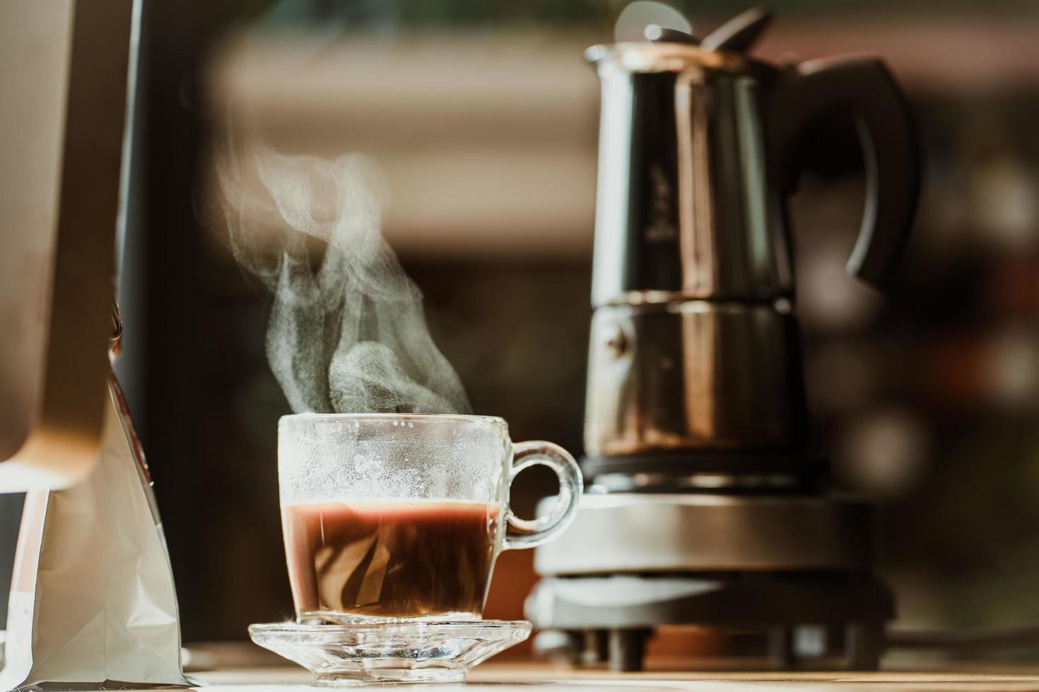 Coffee cup with vintage coffee maker moka pot background on wooden table at home office photo