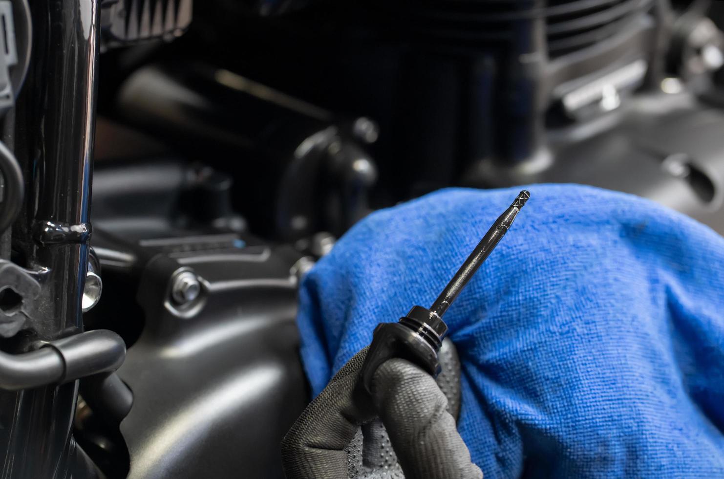 mechanic check engine oil level on big scooter motorcycle in garage .motorcycle repair, maintenance and service concept photo