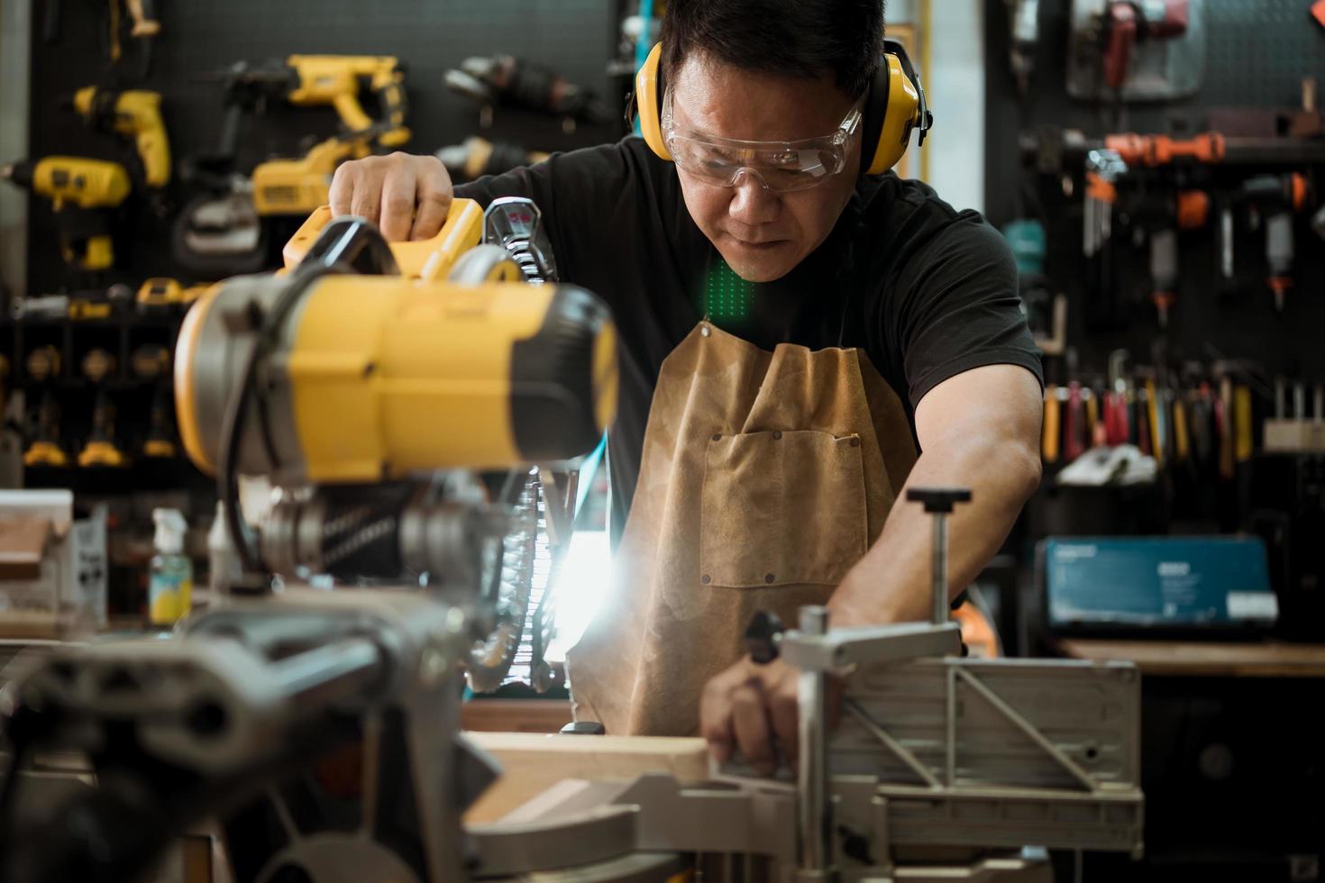 Carpenter cutting wooden with a miter saw or circular saw in shop, woodworking repair and construction tool concept ,selective focus photo