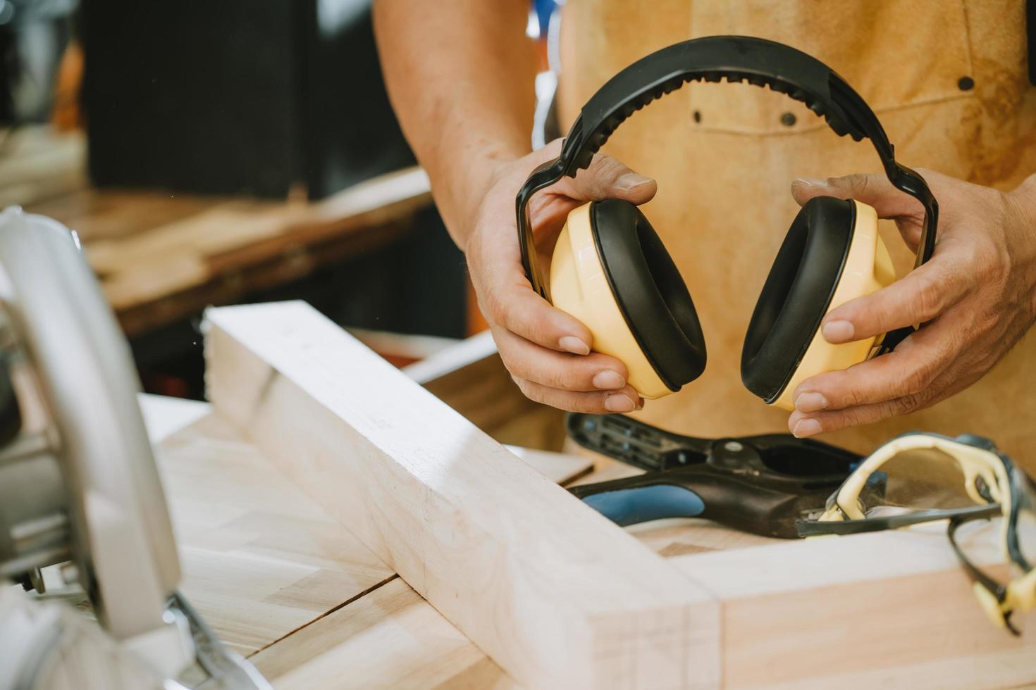 carpenter holding Protective ear muffs in the workshop ,DIY maker and woodworking concept. selective focus photo