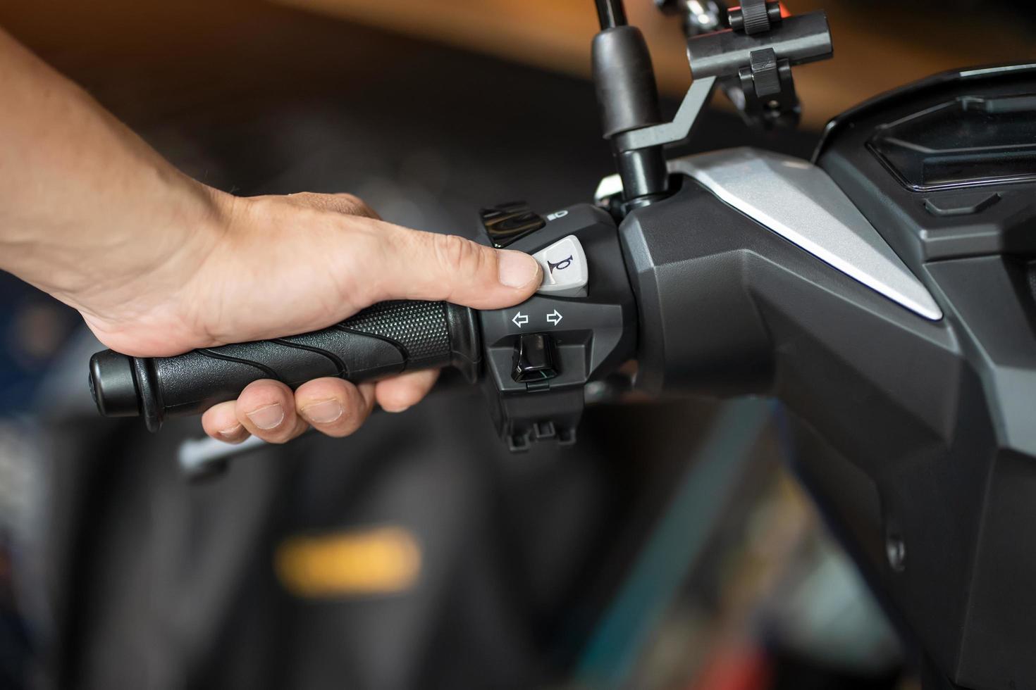 rider holding handlebar and pressing the horn button on motorcycle, repair motorcycle concept in garage.selective focus photo