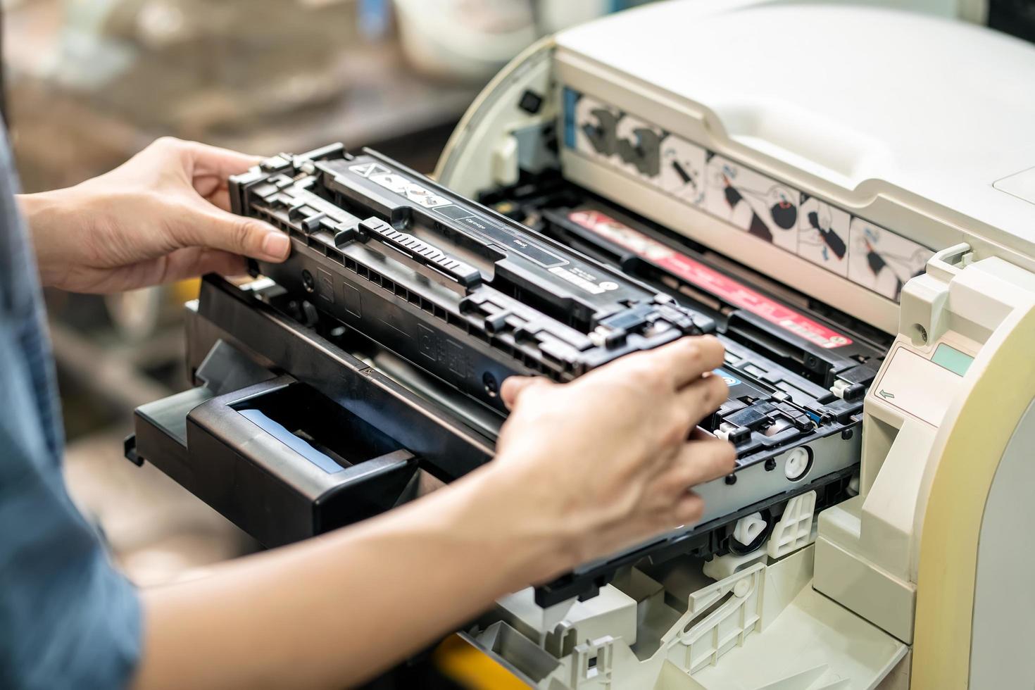 mujeres sosteniendo un cartucho de tóner láser, reemplazando el tóner en la impresora láser en la oficina. concepto de reparación y mantenimiento de impresoras láser foto