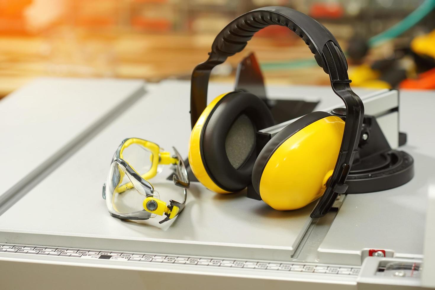 Earmuffs and Safety glasses on Electric saw table in workshop .Work safety concept . selective focus photo