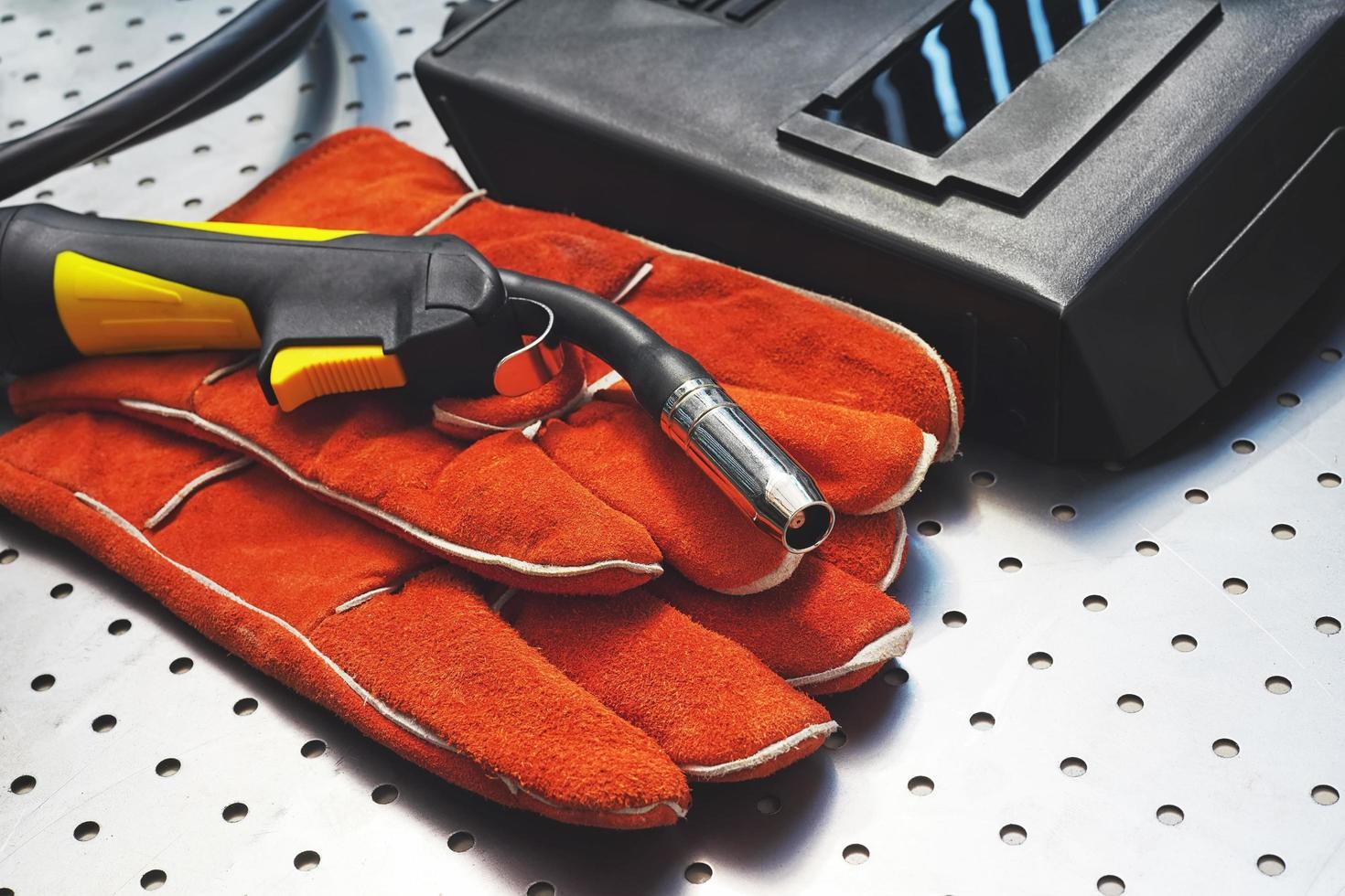 MIG MAG welding gun,leather gloves and welding mask on metal desk photo