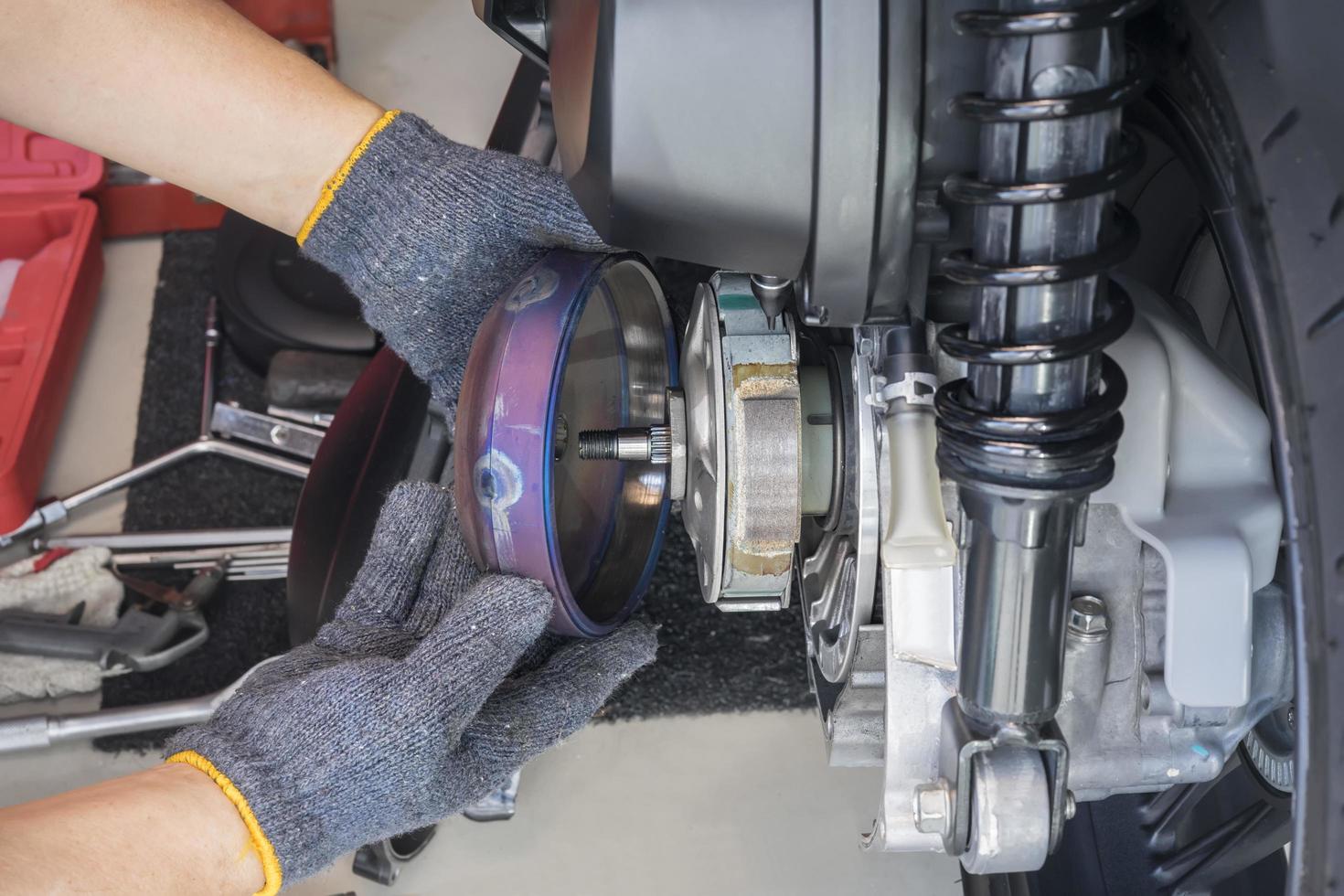 Mechanic working in garage, cleaning and Repairing Rear Clutch system of big scooter motorcycle ,repair and maintenance motorcycle concept.selective focus photo