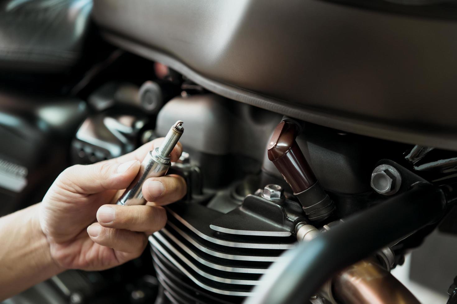 comprobación mecánica de la bujía y mantenimiento de la motocicleta, inspección antes de la instalación en el encendido del motor en el garaje de motocicletas.reparación y mantenimiento del concepto de motocicleta. foto