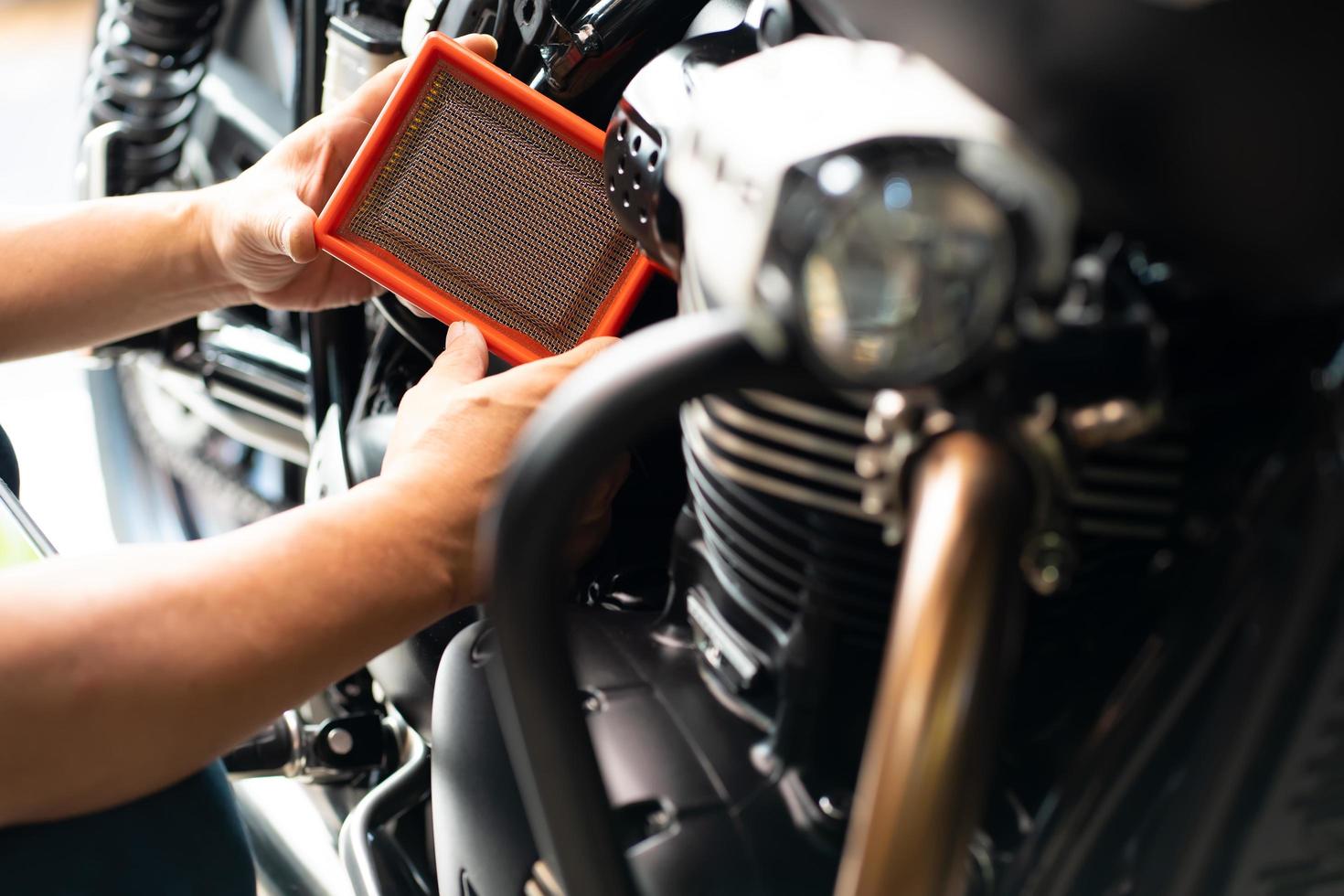 mechanic holding dirty Engine Air Filter over motorcycle, scooter  .mechanic working in garage. Repair and maintenance motorcycle concept photo