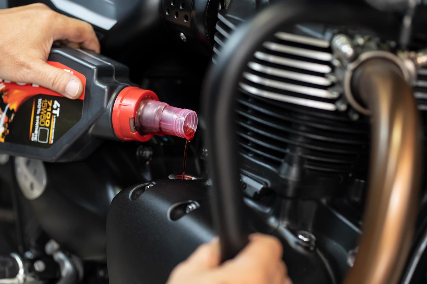 Mechanic Check and pouring engine oil to motorcycle at garage, Motorcycle maintenance and service and repair concept . selective focus . photo