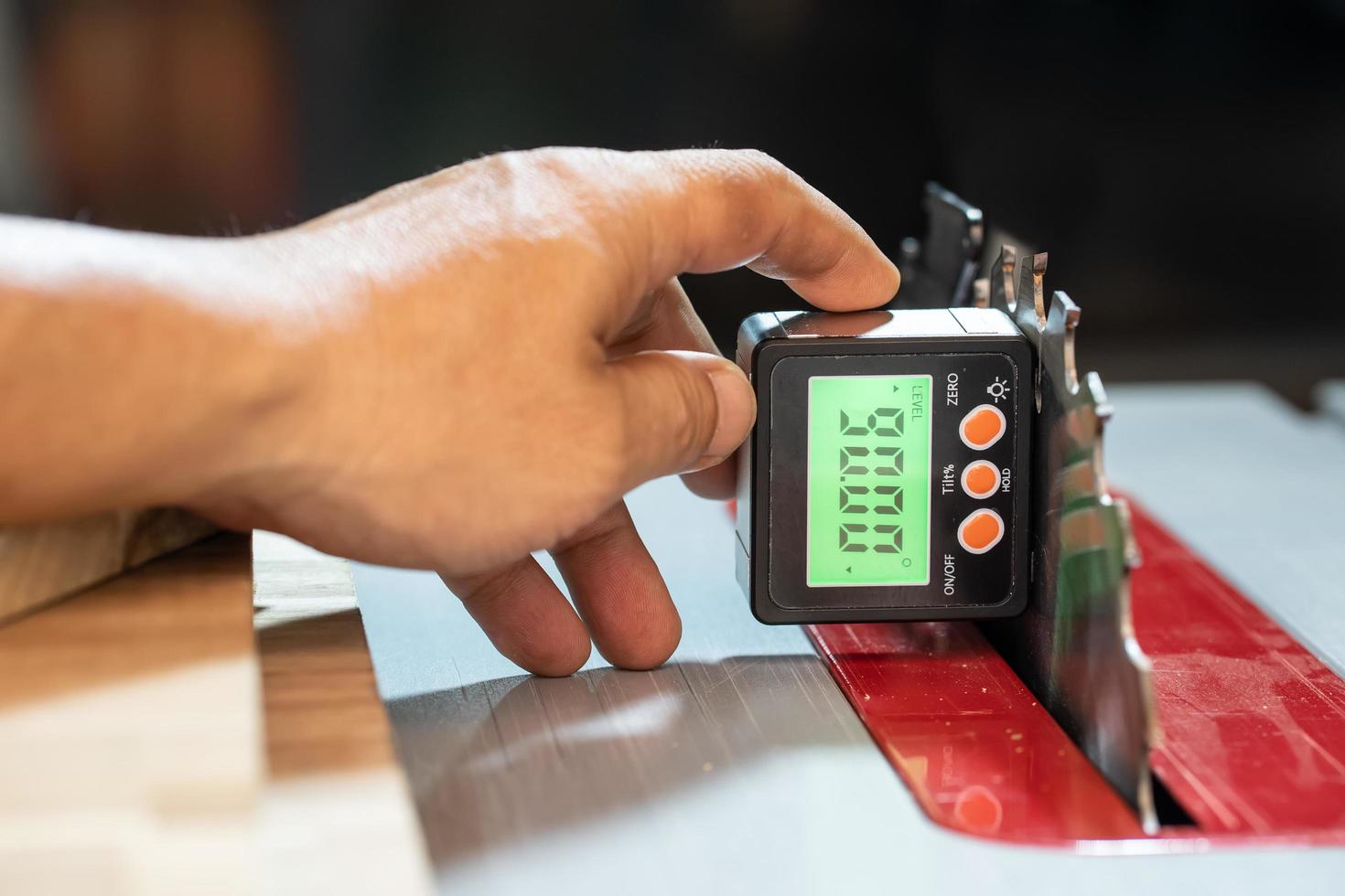 carpenter use Horizontal Angle Meter or Digital Inclinometer to align blades and fences on tablesaw at workshop,woodworking concept.selective focus. photo