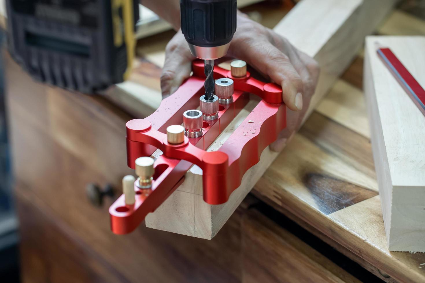 carpenter use drill bit and centering dowel jig tool to make strong joints . woodworking concept.selective focus. photo