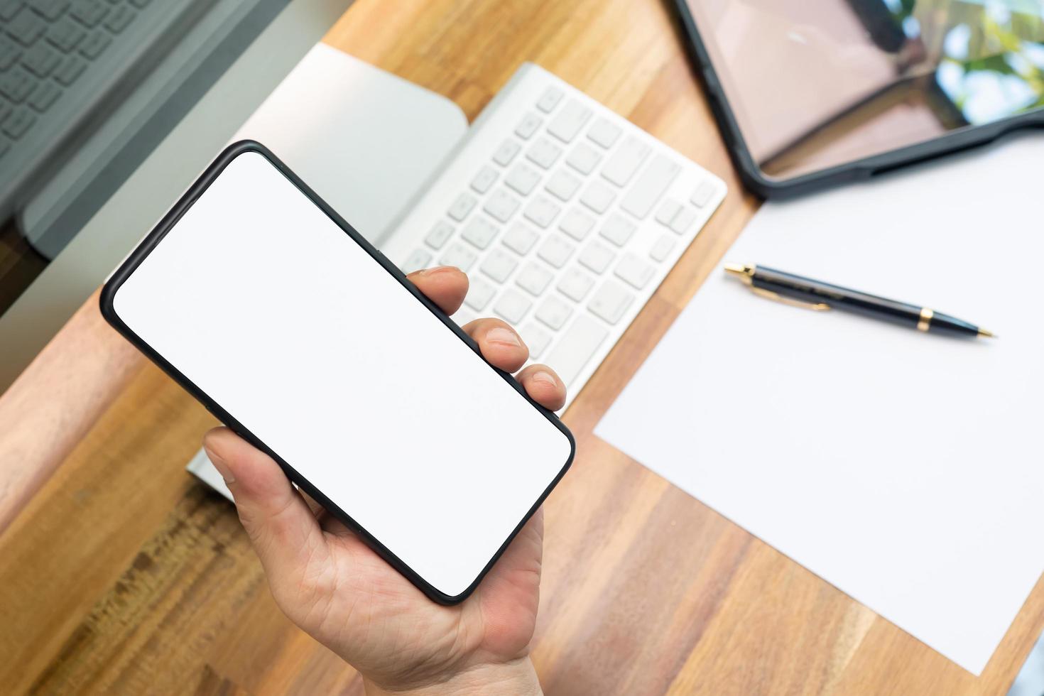 hand holding smartphone with blank screen near working desk,Social media ,communication,technology device concept photo