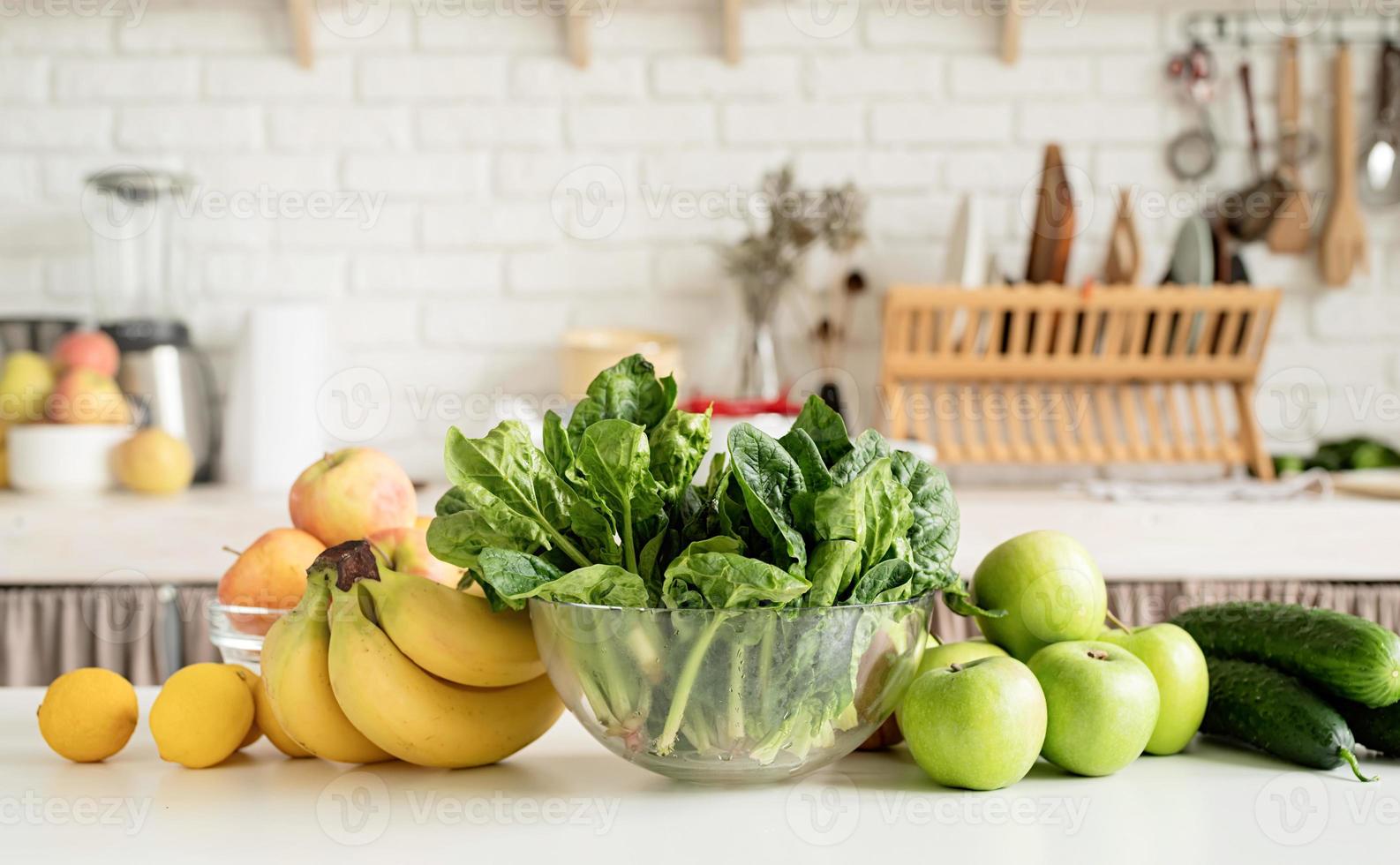 Close up of table with green vegetables and fresh fruit in the kitchen photo