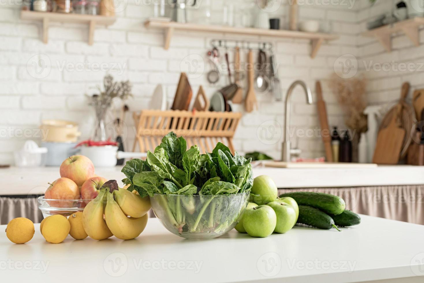 Close up of table with green vegetables and fresh fruit in the kitchen photo