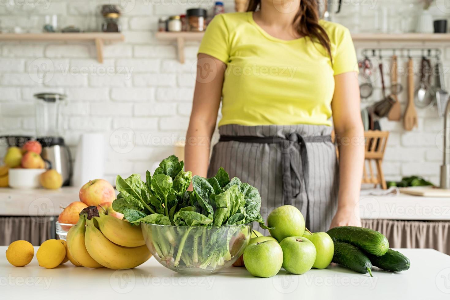 Close up of table with green vegetables and fresh fruit in the kitchen photo