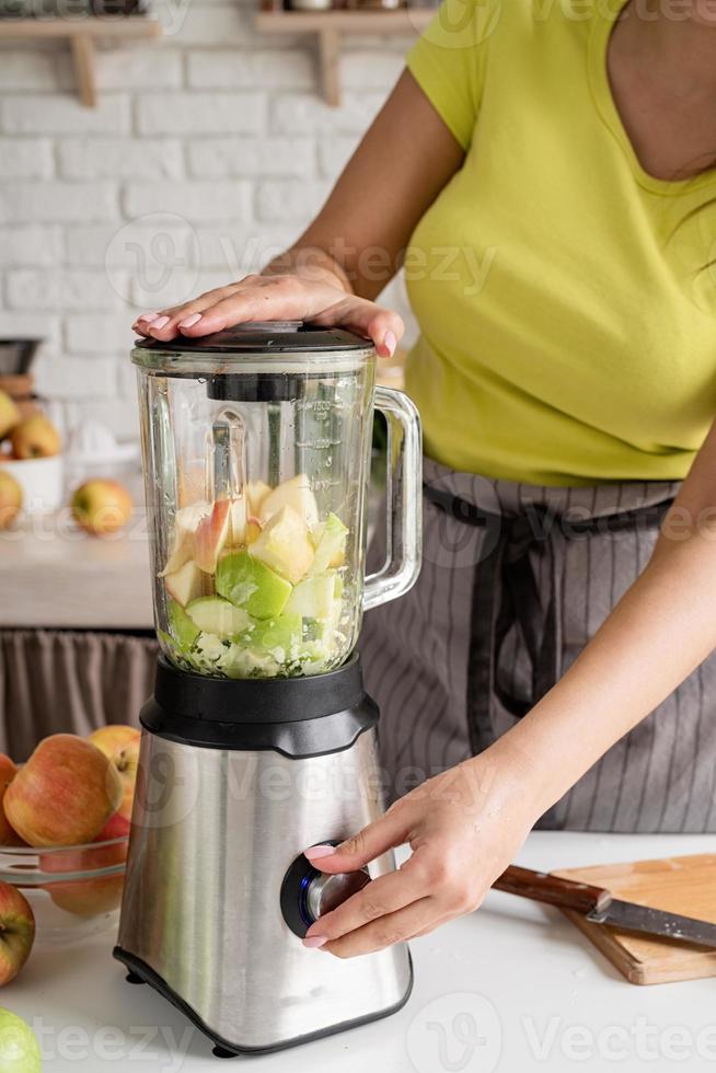 Young woman making banana smoothie at home kitchen photo