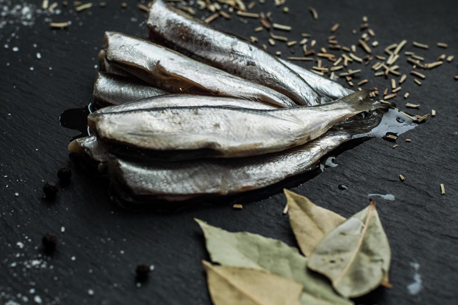 Fresh oiled sardines on black table with spices photo