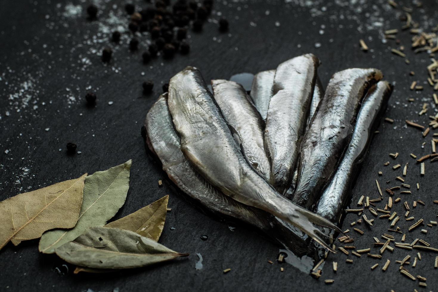 Fresh oiled sardines on black table with spices photo