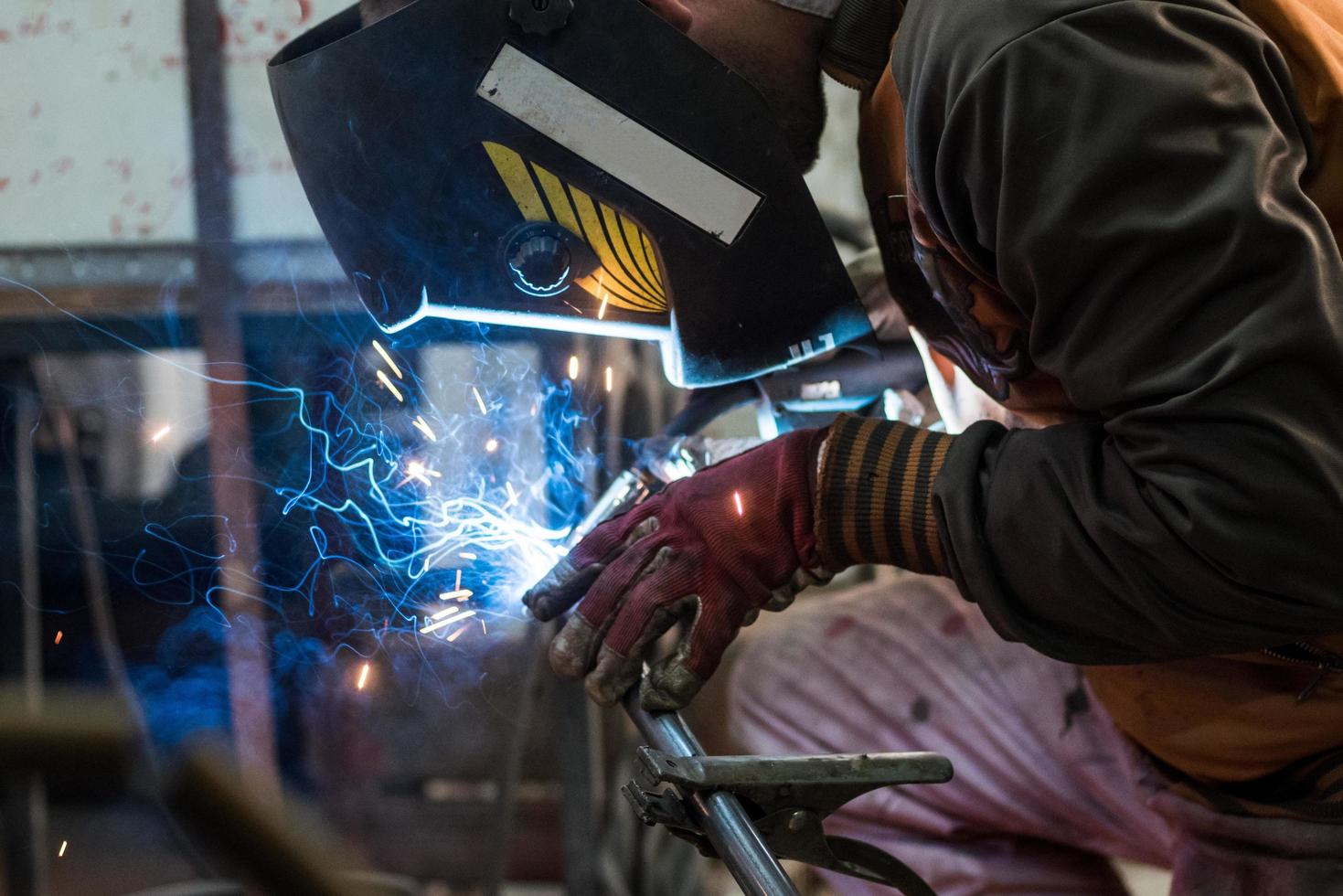 Workers in the mask are welding steel in workshop photo