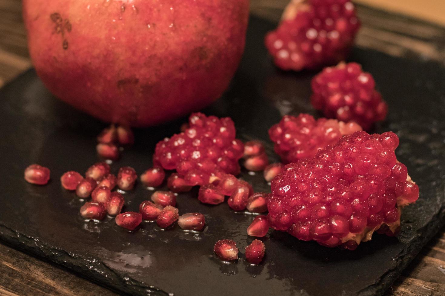 Fresh colorful pomegranates fruits close up on black table photo