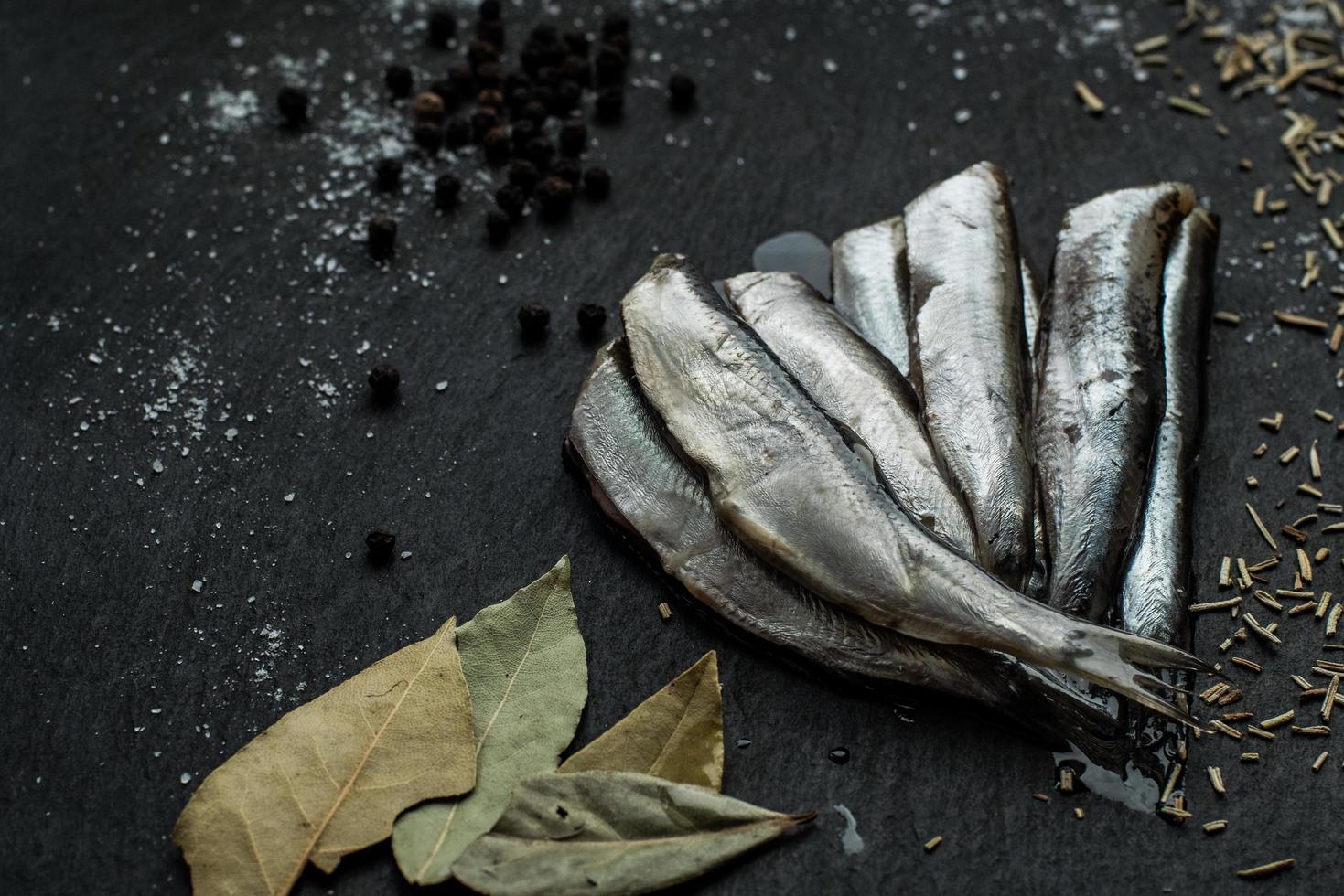 Fresh oiled sardines on black table with spices photo