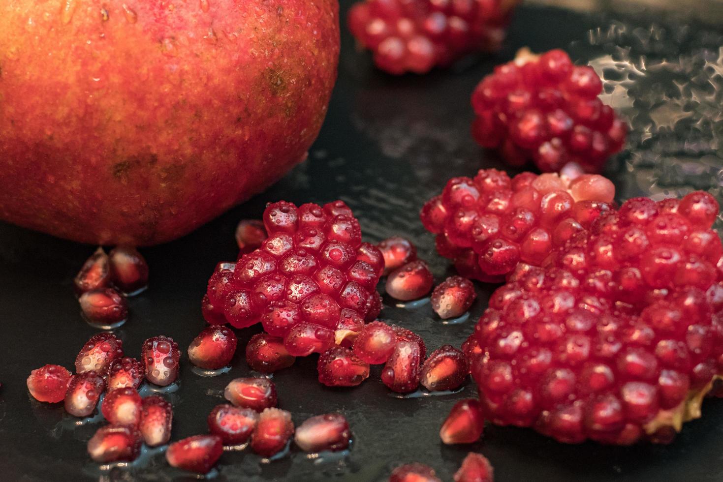 Fresh colorful pomegranates fruits close up on black table photo