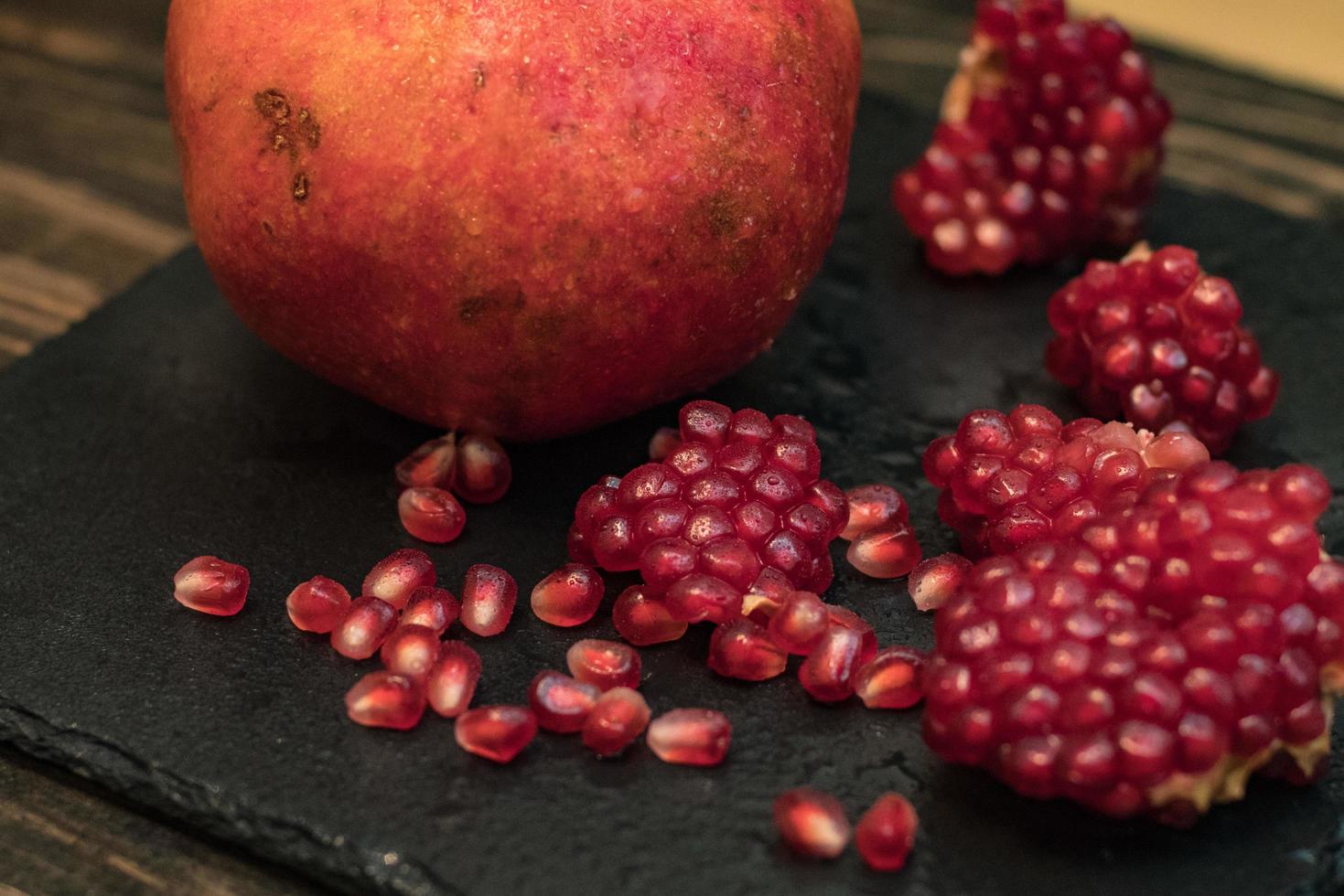 Fresh colorful pomegranates fruits close up on black table photo