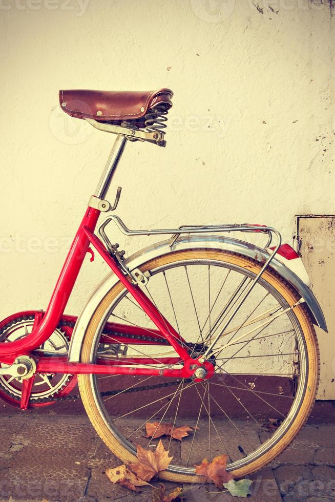 bicicleta retro con hojas de otoño en la rueda trasera. estilo vintage. imagen vertical foto