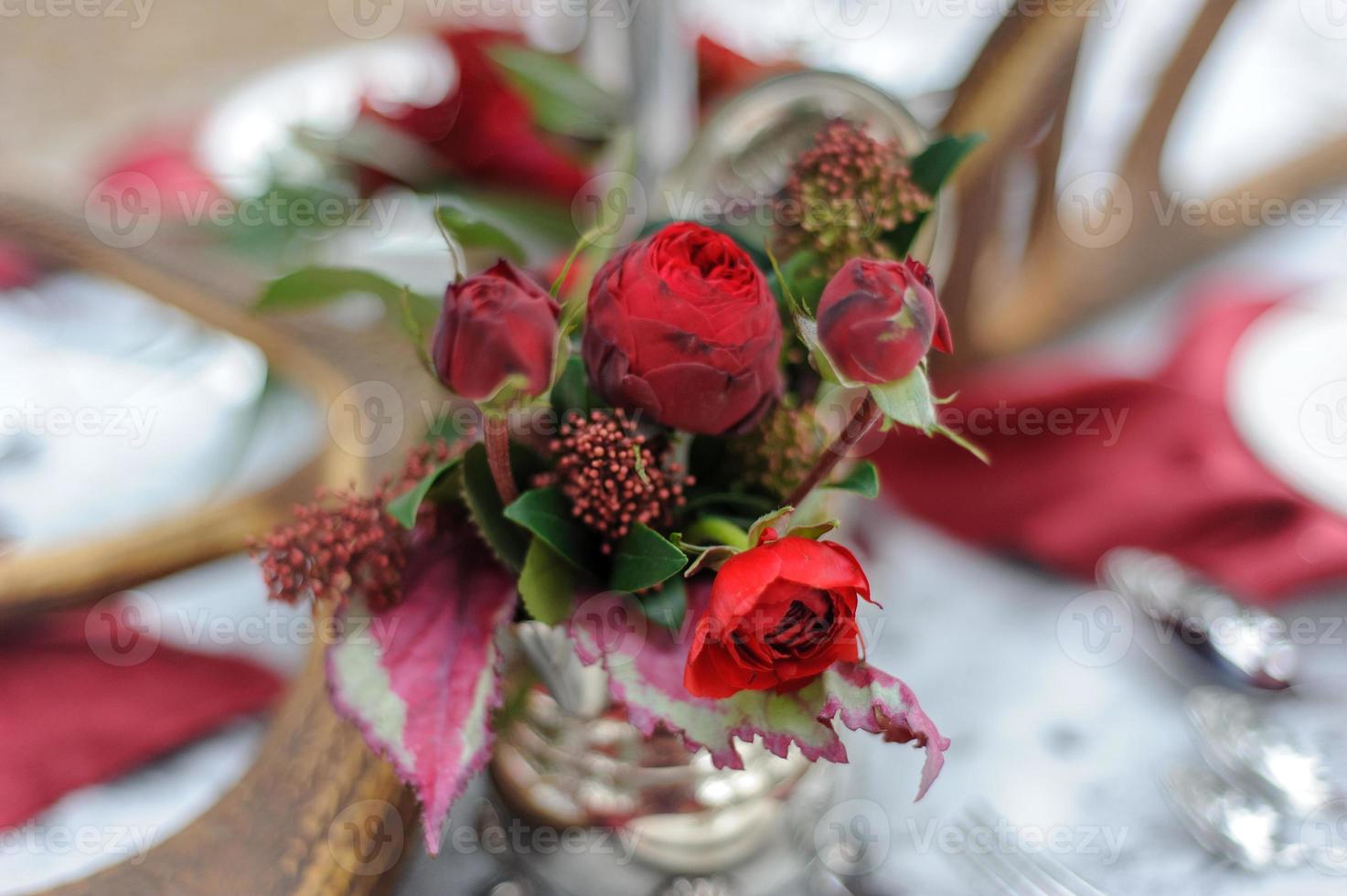Wedding decorations for the ceremony in the street in the winter. A table, candles, dishes, brightly red colors. photo