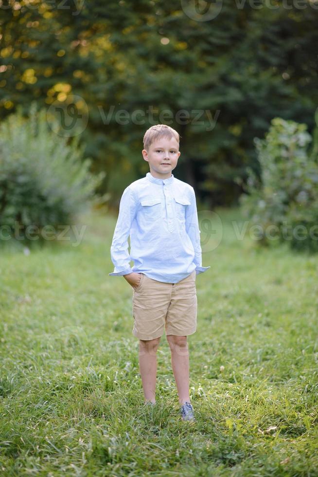 A boy of primary school age runs with balloons. The boy celebrates his birthday in the park. photo