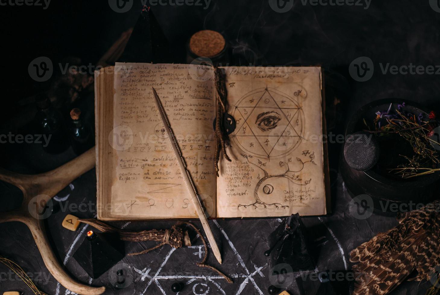 Open old book with magic spells, runes, black candles on witch table. Occult, esoteric, divination and wicca concept. photo