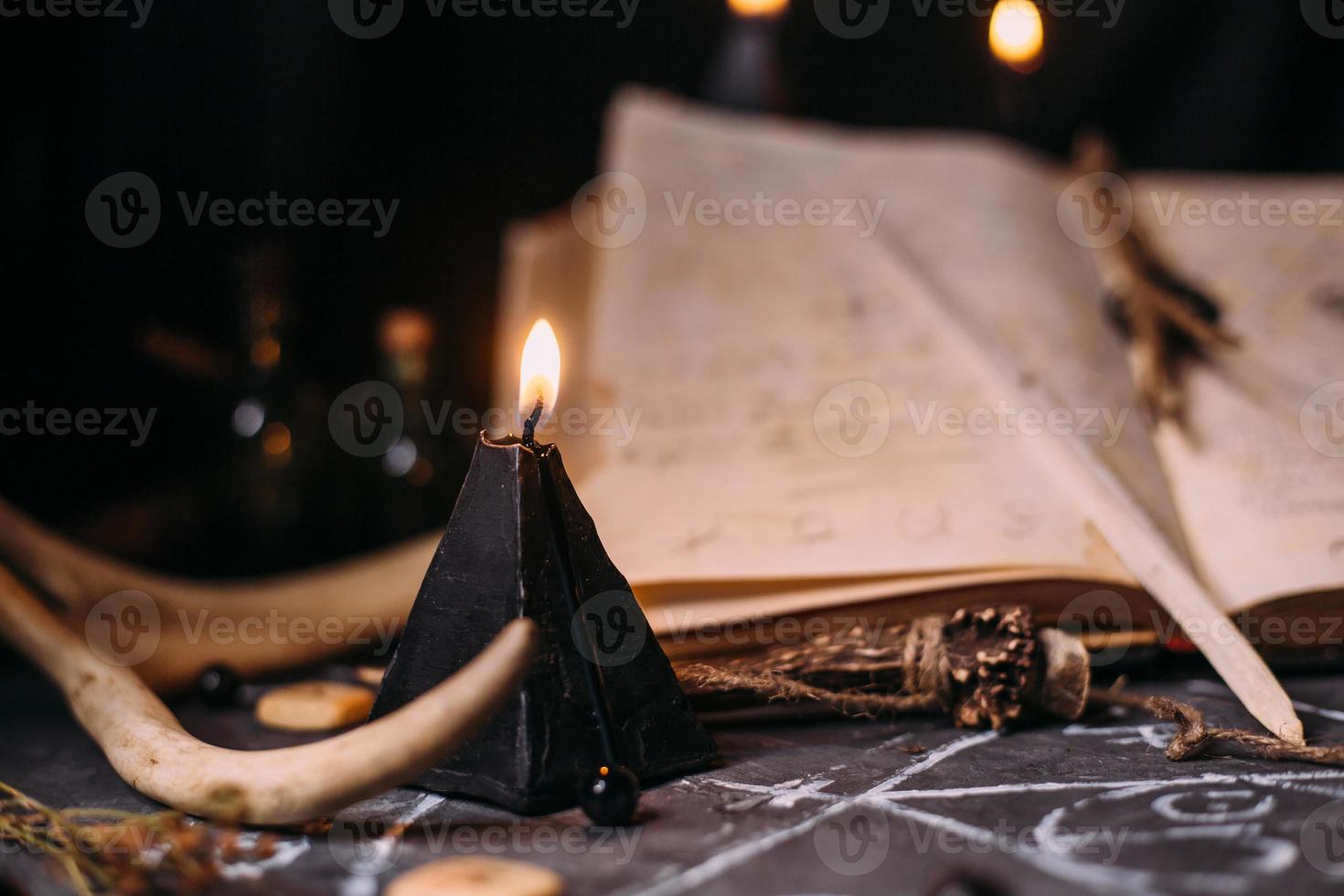 libro viejo abierto con hechizos mágicos, runas, velas negras en la mesa de brujas. concepto oculto, esotérico, adivinación y wicca. foto