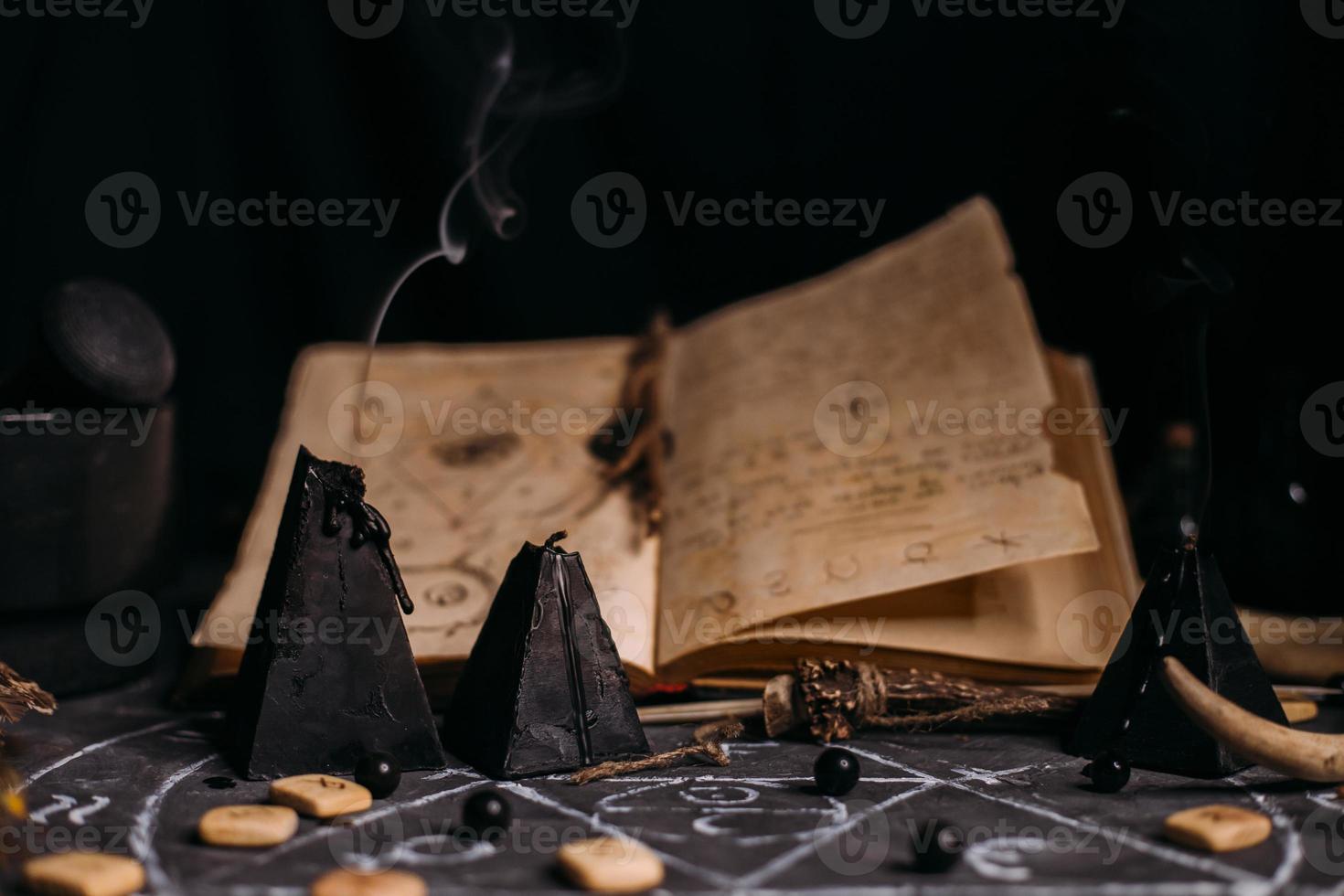 Open old book with magic spells, runes, black candles on witch table. Occult, esoteric, divination and wicca concept. photo