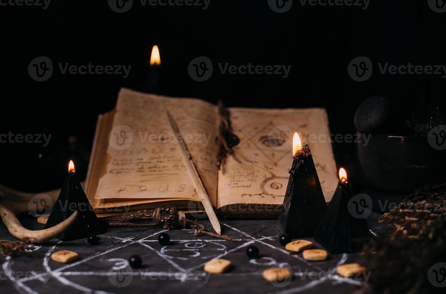 Open old book with magic spells, runes, black candles on witch table. Occult, esoteric, divination and wicca concept. photo