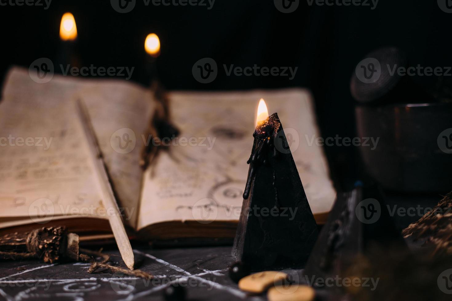 Open old book with magic spells, runes, black candles on witch table. Occult, esoteric, divination and wicca concept. photo