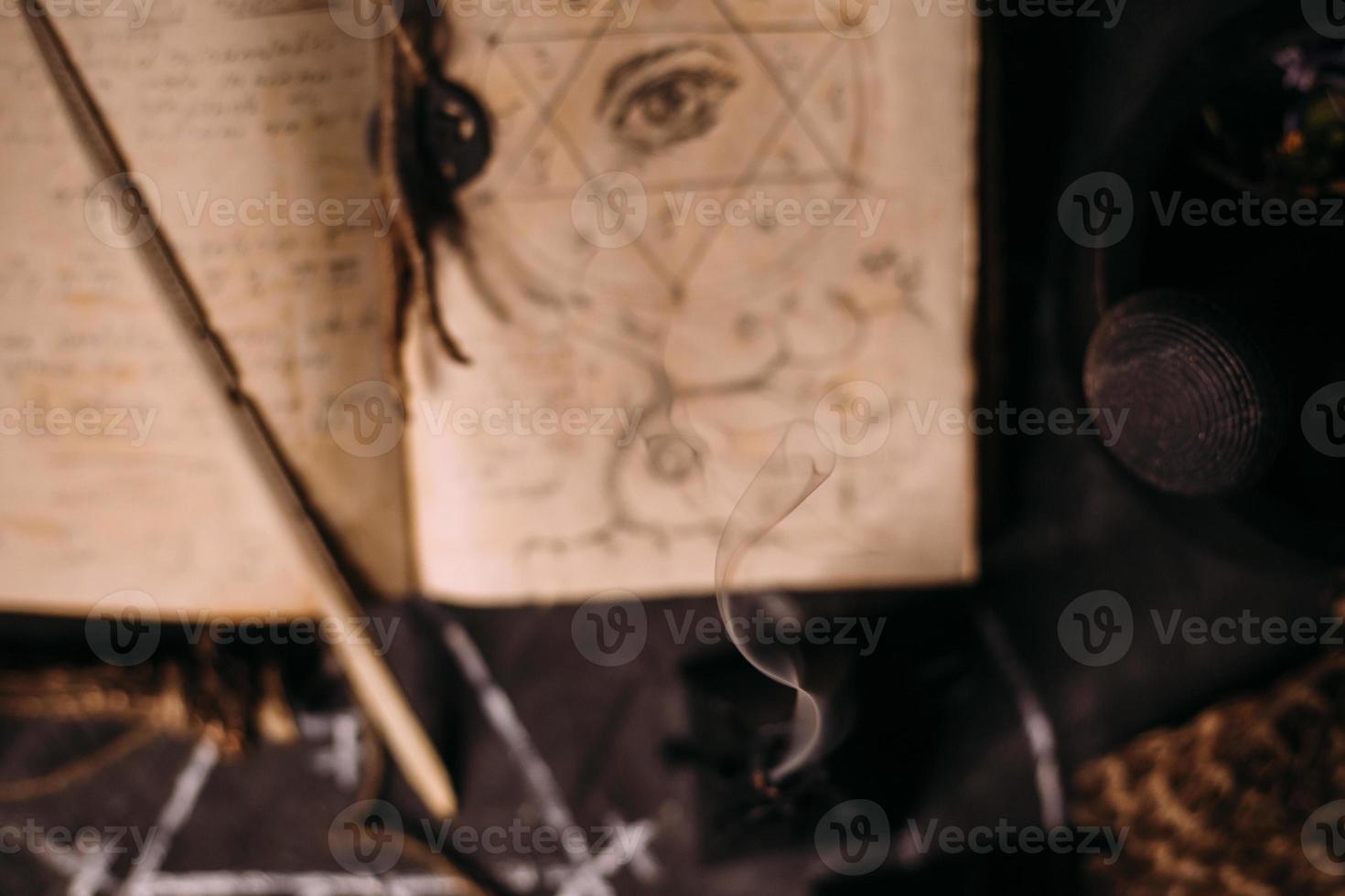 Open old book with magic spells, runes, black candles on witch table. Occult, esoteric, divination and wicca concept. photo