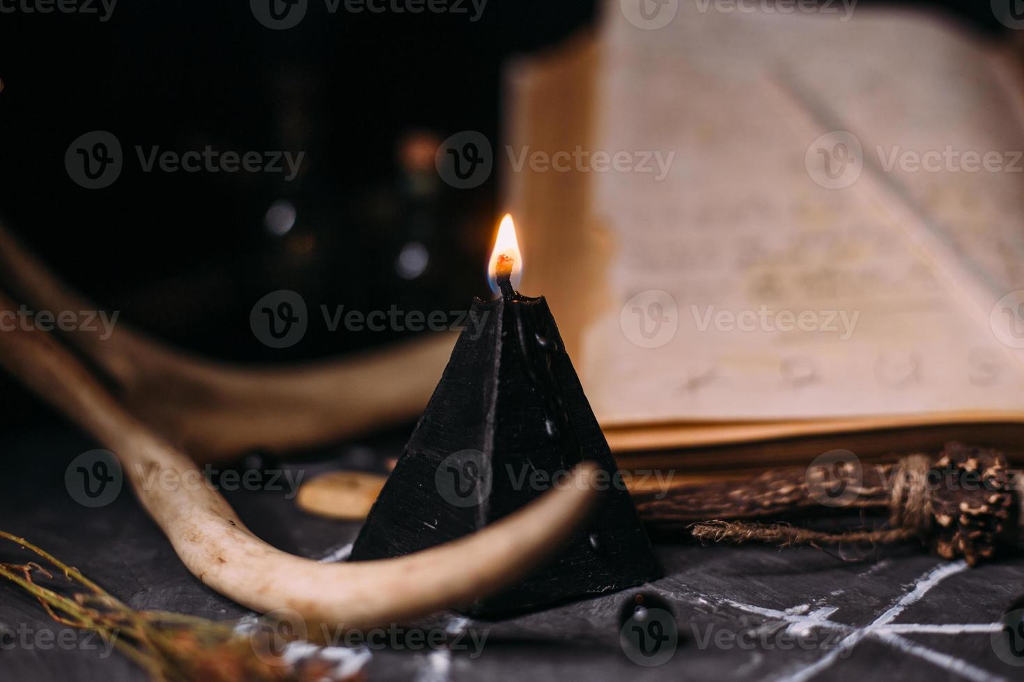 Open old book with magic spells, runes, black candles on witch table. Occult, esoteric, divination and wicca concept. photo