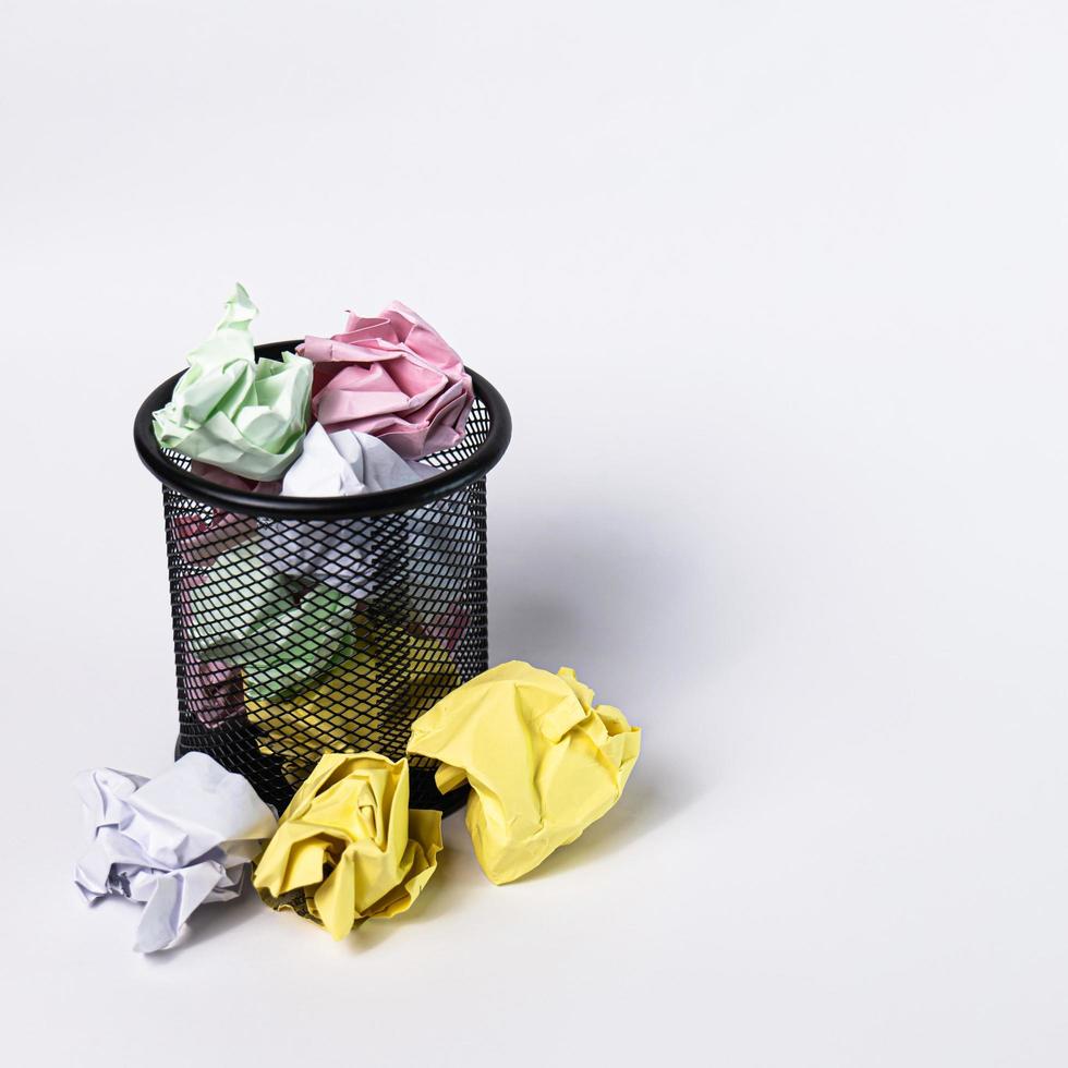 A small black basket made of round steel. Used to put garbage, documents that are not work and have been crushed so much that it overflows outside. In the white background there is copy space. photo
